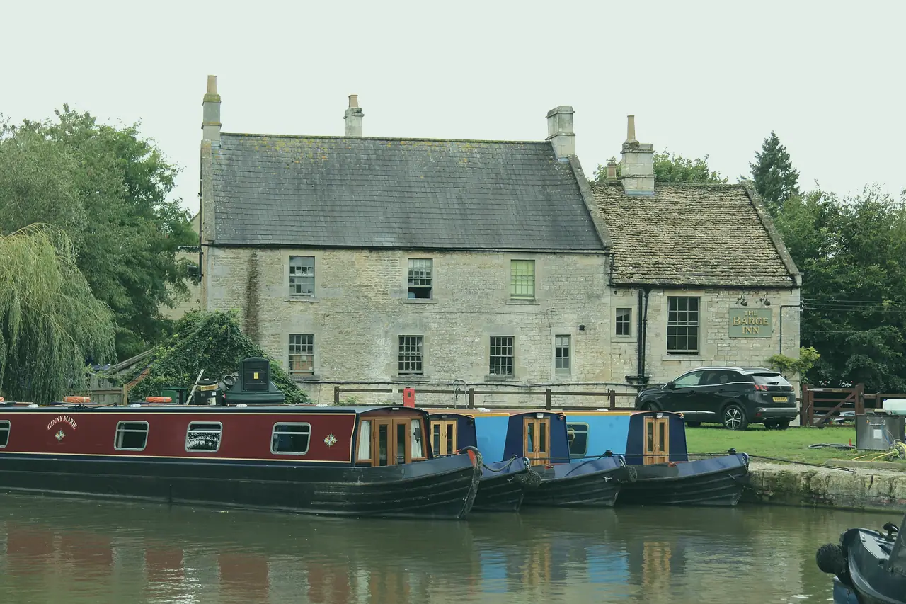 Red and blue narrowboats moored beside an old stone inn
